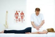 Chiropraktiker bearbeitet mit beiden Händen den Rücken einer auf dem Bauch liegenden Frau Chiropraktiker bearbeitet mit beiden Händen den Rücken einer auf dem Bauch liegenden Frau